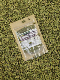 Envase de cardamomo entero sobre abundantes vainas verdes